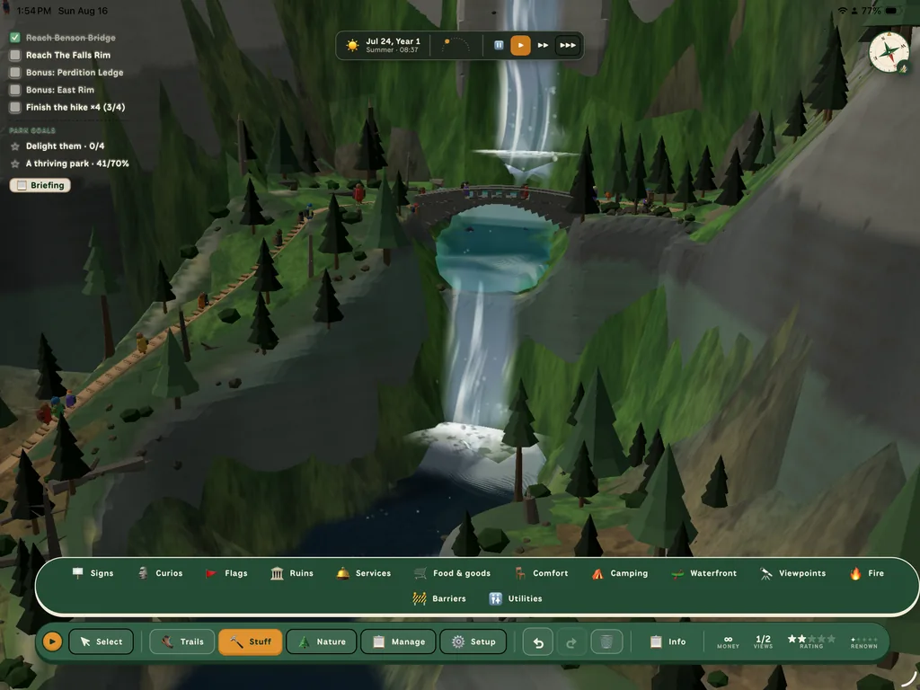 Hikees crossing a stone arch bridge between two waterfalls, a boardwalk trail switchbacking up the slope beside them